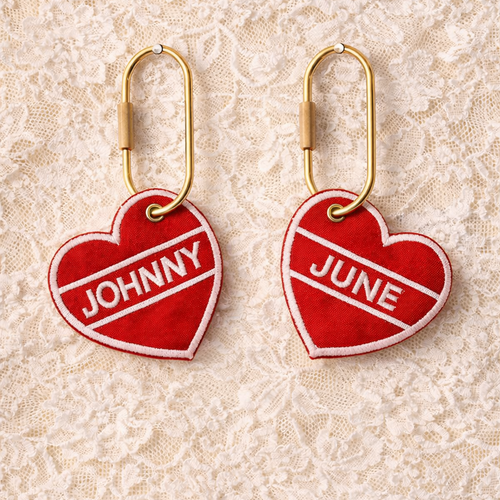 Red heart-shaped earrings with 'JOHNNY' and 'JUNE' text on a lace background