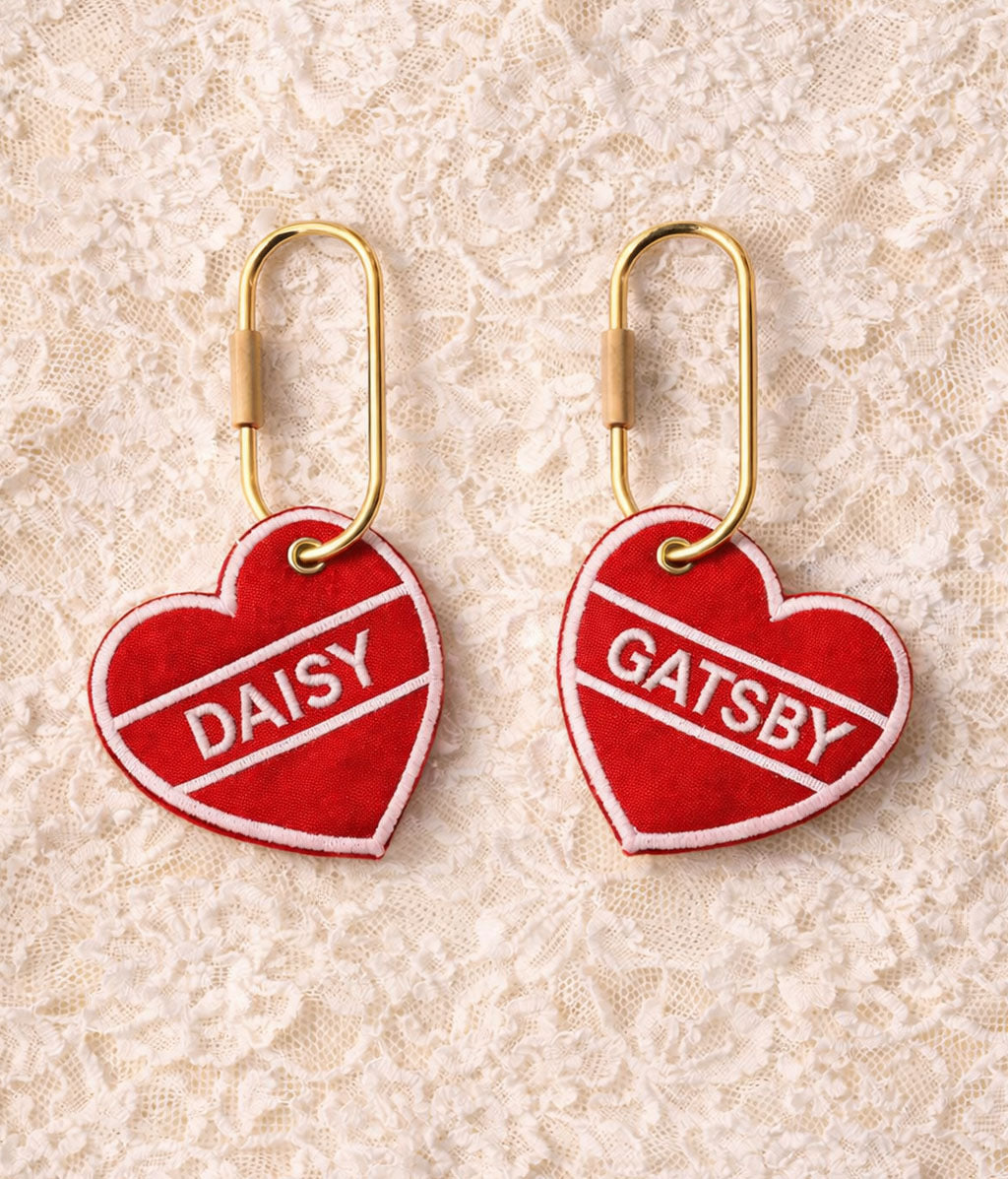 Red heart-shaped tags with 'Daisy' and 'Gatsby' on a lace background