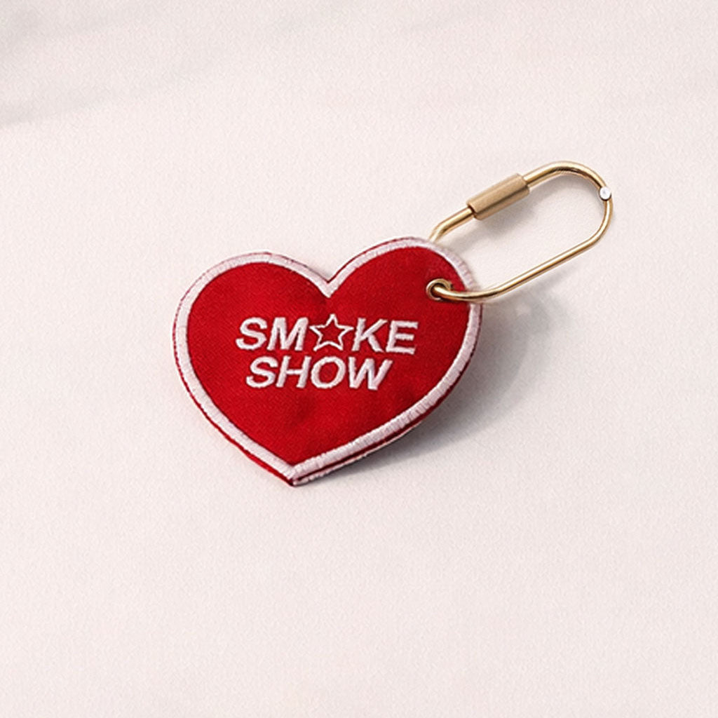 Red heart-shaped keychain with 'SM*KE SHOW' text on a light gray background