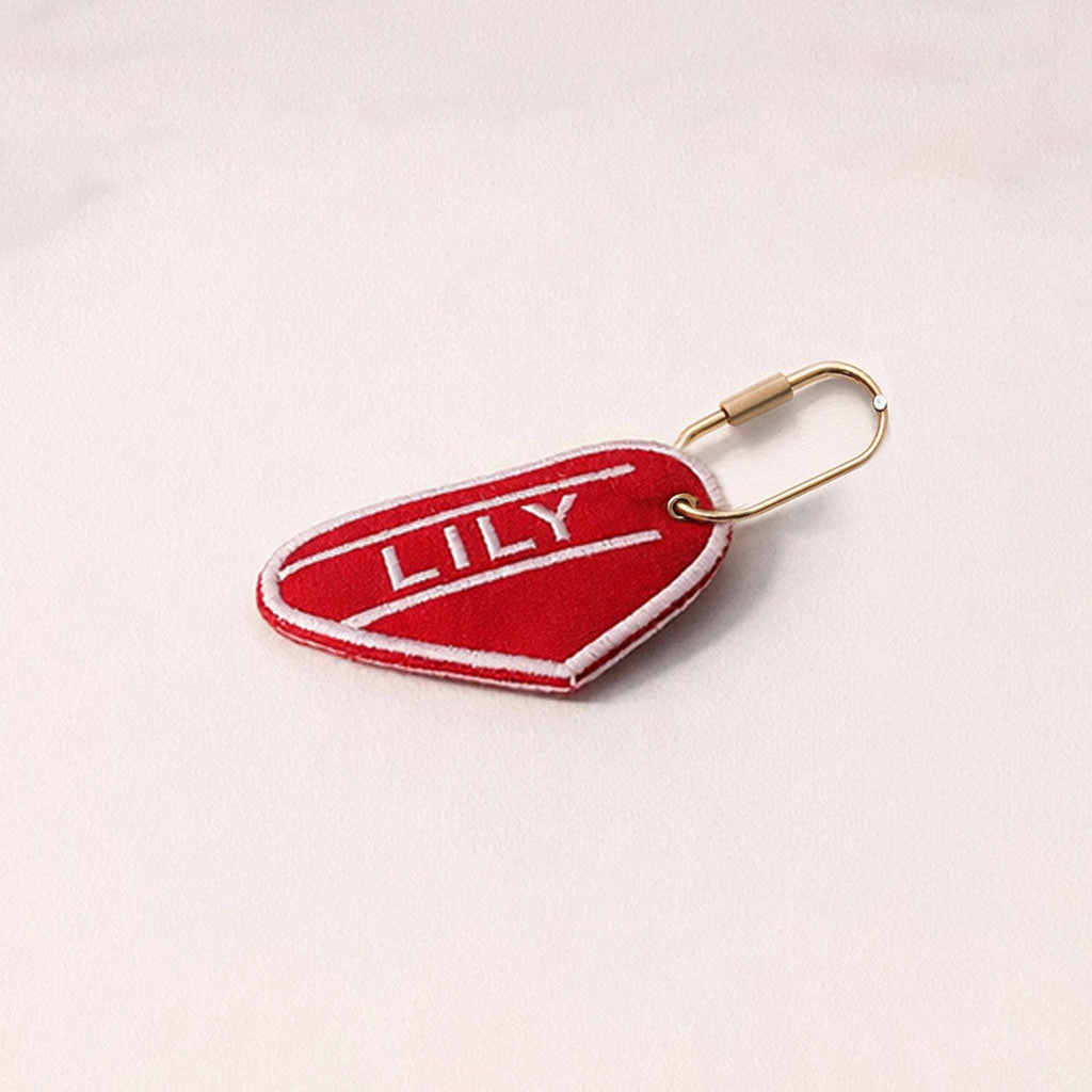 Red keychain tag with 'LILY' on a light pink background